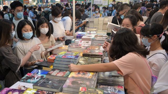 香港书展一书摊上一群读者翻阅中文小说（中新社图片21/7/2022）
