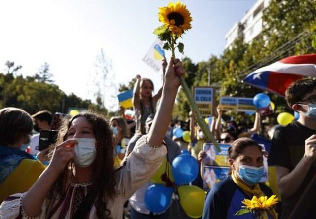 在智利圣地亚哥，抗议者手持乌克兰国花向日葵参加抗议集会(photo:BBC)