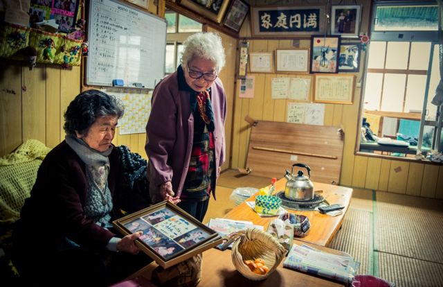 Duas mulheres de Okinawa conversam e olham fotografias
