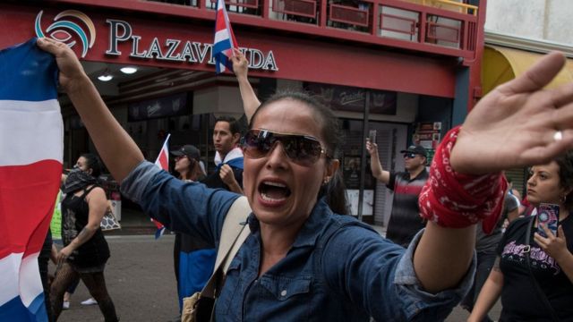 Una mujer con una bandera de Costa Rica en una marcha antiinmigrantes