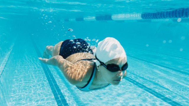 Mulher nadando em piscina debaixo d'gua