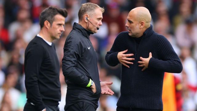 Pep Guardiola speaks to the fourth official as Fulham manager Marco Silva looks on