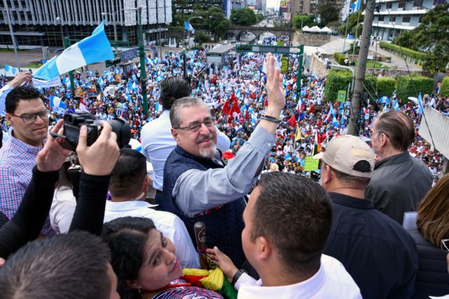 Bernardo Arévalo saluda en un acto rodeado de gente.