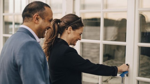 Mulher abrindo porta de casa ao lado de um homem