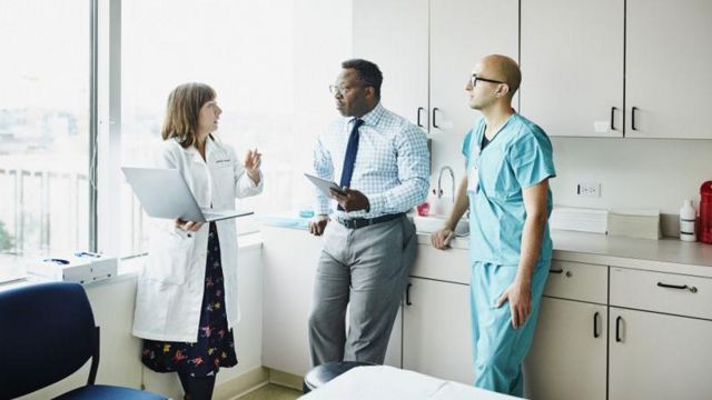 Três pessoas de equipe médica conversando em hospital