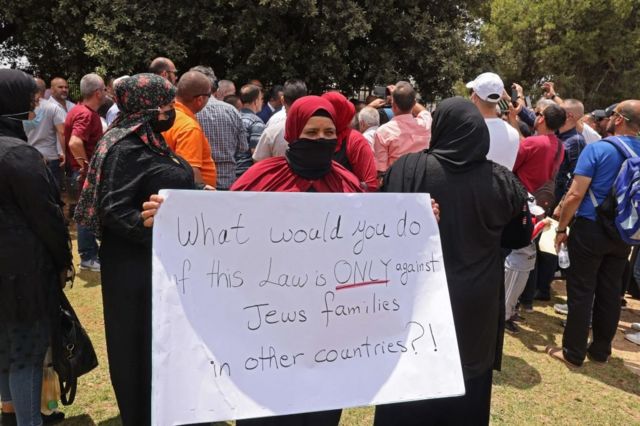 امرأة ترفع لافتة ضد قانون "المواطنة والدخول إلى إسرائيل" خلال مظاهرة لعرب إسرائيل خارج مبنى الكنيست في القدس
