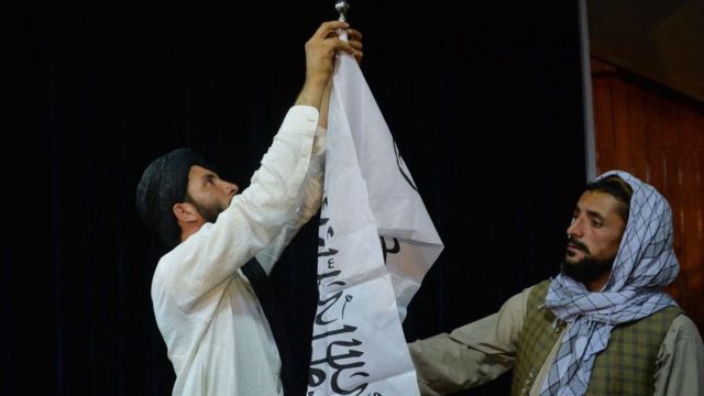 Dos talibanes instalan una bandera en Kabul.