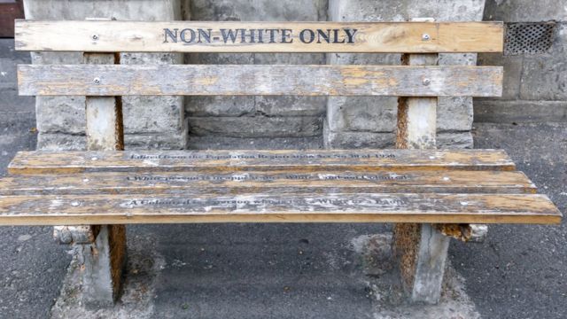 Un banco de madera en Ciudad del Cabo, Sudafrica, en el que se lee "Solo no blancos"