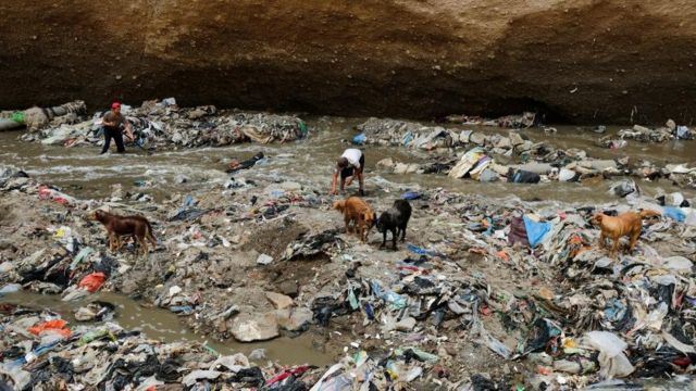 Hombres recolectan chatarra metálica del contaminado río Las Vacas