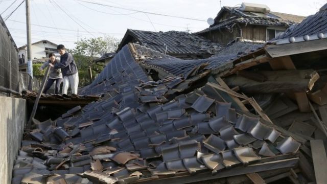 Residents cross over debris of collapsed buildings in Mashiki, south-western Japan. Photo: 16 April 2016