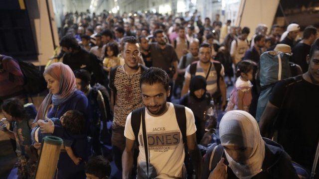 Syrian refugees disembark from a ferry at the port of Piraeus, near Athens