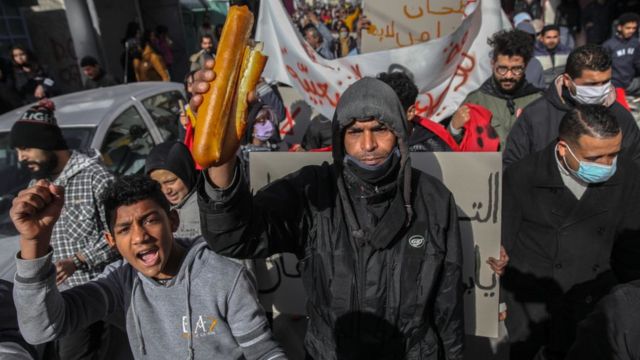 A protester raises a loaf of bread in Tunis