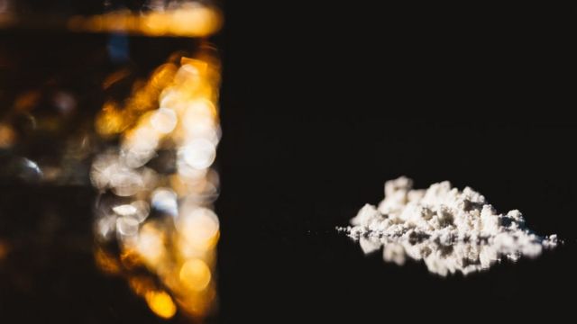 Cocaína em fundo preto e com luzes abstratas ao lado