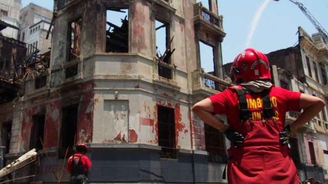 Efectivos de los Bomberos observan el edificio que ardió en el centro de Lima durante las protestas del jueves 19.