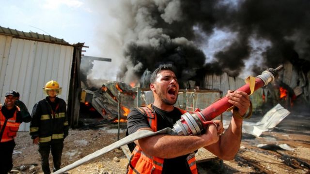 Un bombero palestino tratando de apagar el fuego en el sitio de un bombardeo.