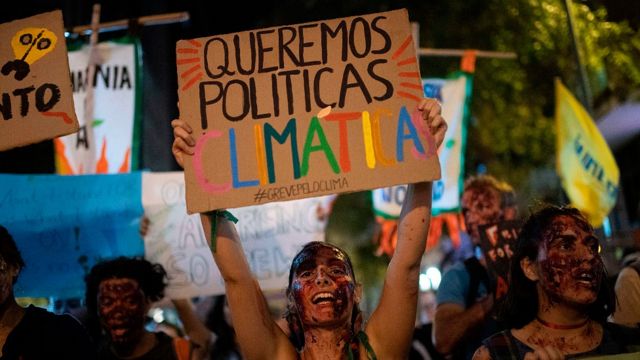 Una joven en Río de Janeiro con una pancarta que dice "queremos políticas climáticas"