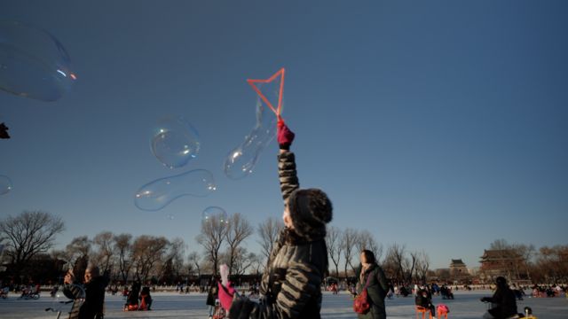 People play with bubbles on a frozen lake in Beijing