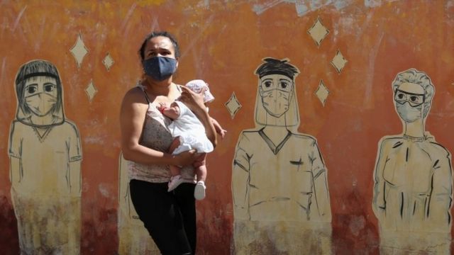 Una mujer con un bebé junto a un mural en Argentina
