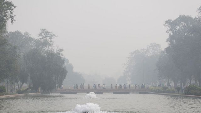 Жители Дели идут через смог