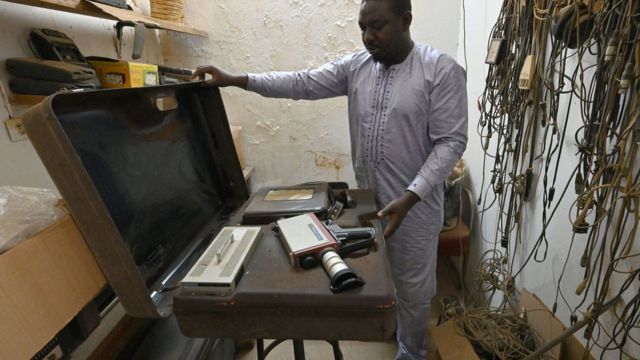 Un homme montre un étui à caméra dans la salle de montage de feu l'ethnographe et cinéaste français Jean Rouch à l'Institut de recherche en sciences humaines (IRSH) de Niamey le 22 février 2021.