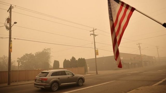 A car and a US flag in the smoke-filled town of Molalla, Oregon