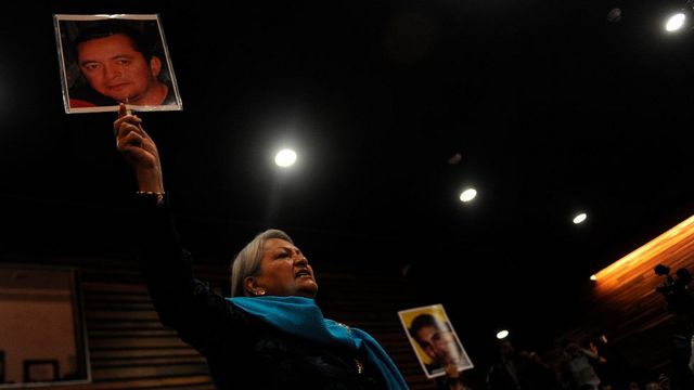 Una mujer levanta una foto de un hombre desaparecido en Coahuila