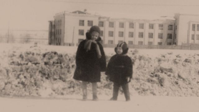 Бывший заключенный колымских лагерей, в 1961 году "не выездной" фотограф-любитель снимает своих детей на фоне здания, которое в годы сталинских репрессий занимала Центральная больница Управления Северо-Восточных Исправительно-трудовых Лагерей в поселке Дебин