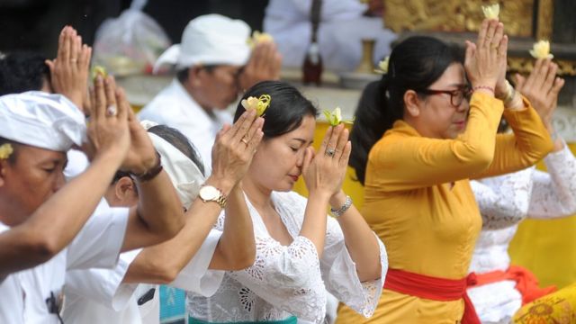 Pemuka agama Hindu memercikkan air suci saat persembahyangan bersama di Pura Luhur Candi Narmada Tanah Kilap, Denpasar, Bali, Jumat (31/01) untuk memohon agar Bali dijauhkan dari penyebaran virus Corona.