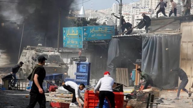 شباب فلسطينيون يلقون حجارة وأشياء أخرى على ناقلات جند مدرعة إسرائيلية