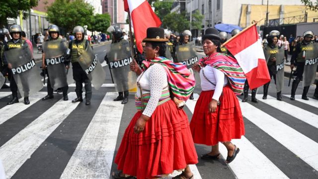 Manifestantes nas ruas carregando a bandeira do Peru