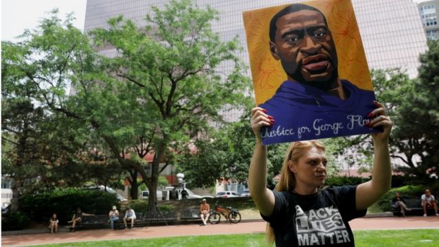 George Floyd'un pankartını tutan bir genç kadın