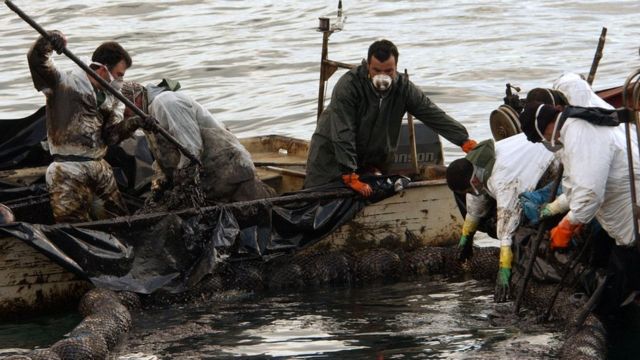 Pescadores recogiendo fuel del mar en Galicia