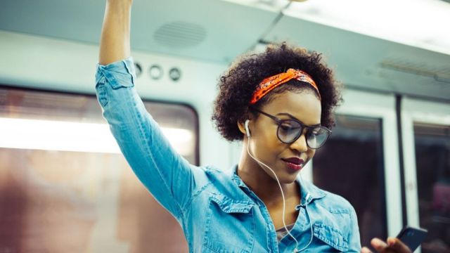 Una mujer con audífonos en el metro