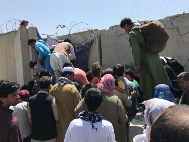 As pessoas tentam ultrapassar o muro do Aeroporto Internacional Hamid Karzai