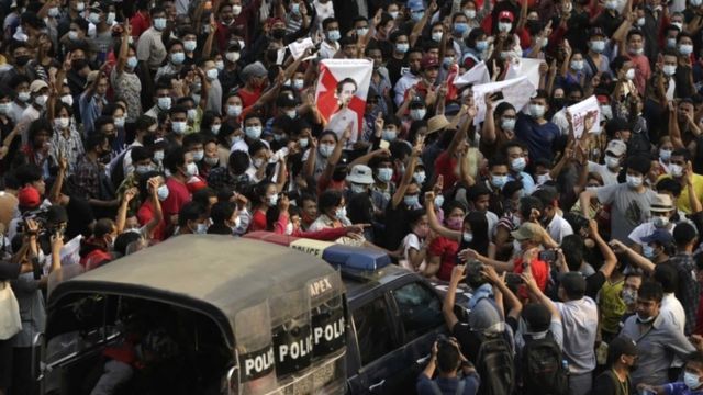 A police car runs through the protesters