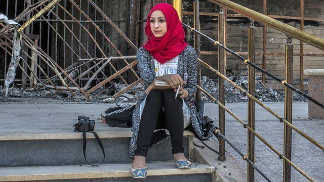 Student outside damaged building in Mosul University