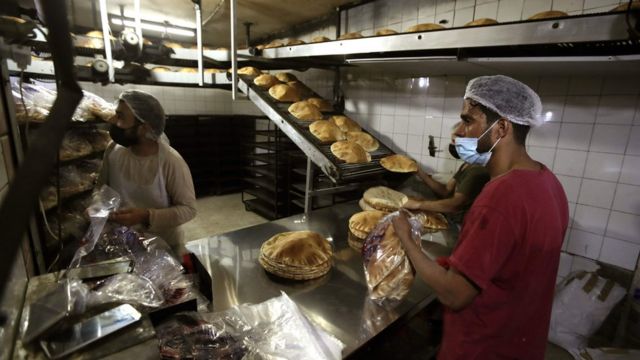 Bakers package workers package freshly-produced bread coming off a production line at an automated bakery in Lebanon"s capital Beirut (1 July 2020)