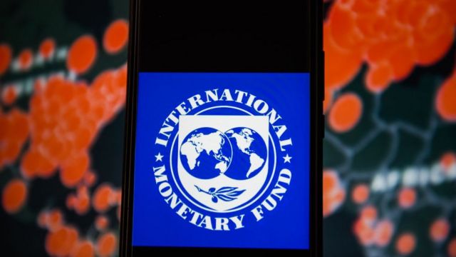 Logo del FMI frente a un mapa de casos de covid-19