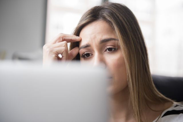 Mulher com olhar de preocupação em frente ao laptop