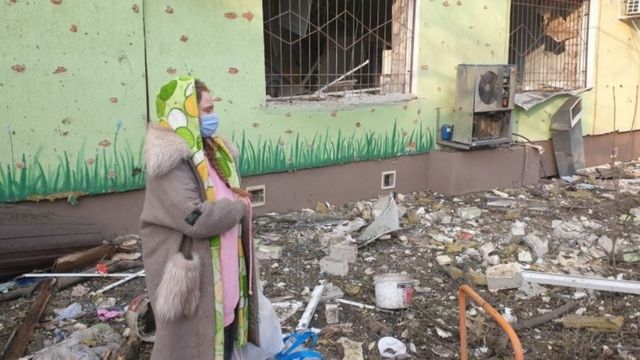 Mulher entre escombros em Mariupol