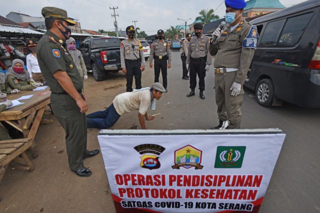 Personel Polisi Pamong Praja disaksikan anggota Polri memberi hukuman push-up kepada warga yang tidak memakai masker saat Operasi Pendisiplinan Protokol Kesehatan di Jalan Cimuncang, Serang, Banten, Selasa (15/09)