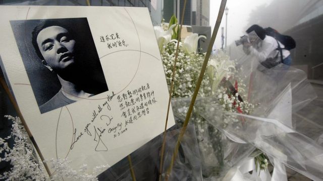 People leave flowers in memory of entertainer Leslie Cheung prior to queuing outside Madame Tussaud waxworks in Hong Kong for a viewing of the waxwork model of Cheung, 31 March 2004