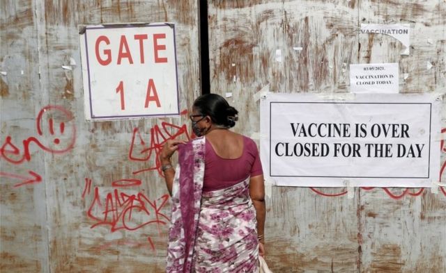 امرأة جاءت لتلقي جرعة من لقاح فيروس كورونا، تقف أمام بوابة مغلقة لمركز التطعيم الذي تم إغلاقه بسبب عدم توفر لقاح، في مومباي ، الهند ، 3 مايو 2021.