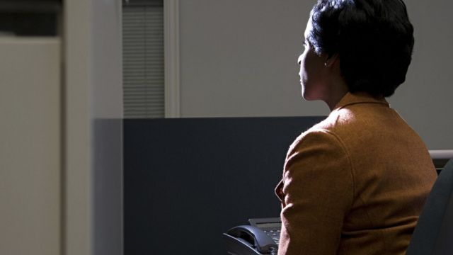 Mujer en su escritorio mirando por la ventana.