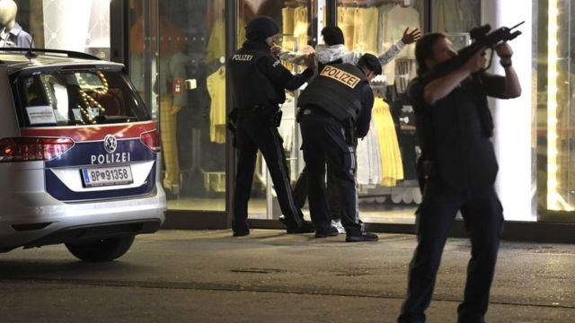 Police officers search a person while patrolling a street