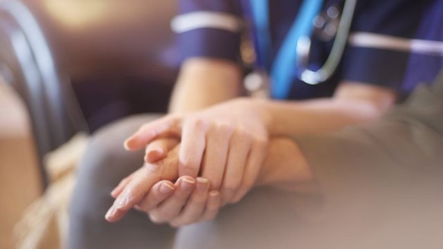 Una enfermera sostiene la mano de un paciente