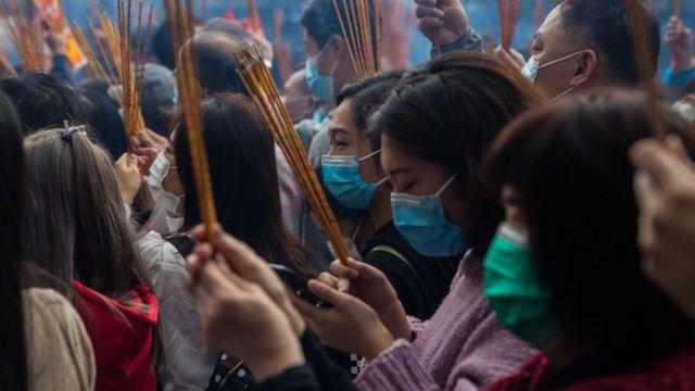 Personas con mascarillas rezando.