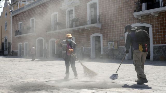 Trabajadores de limpieza en Puebla retirando cenizas volcánicas de las calles.