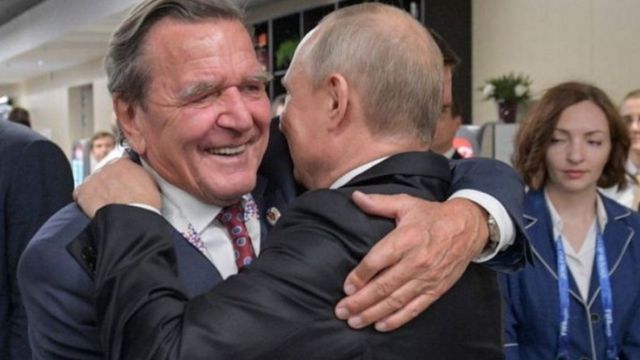 غيرهارد شرودر (اليسار) يعانق الرئيس الروسي بوتين أثناء افتتاح كأس العالم لكرة القدم في موسكو عام 2018