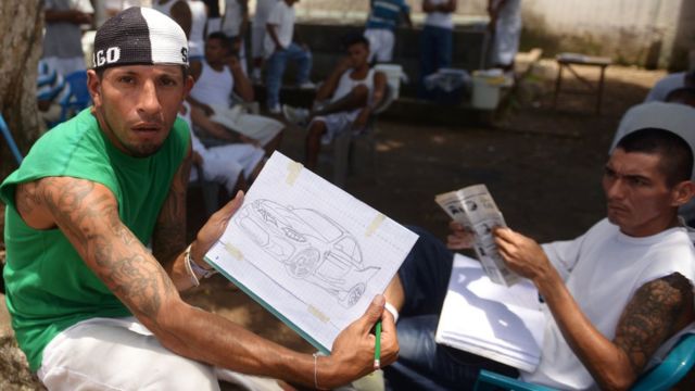 Reclusos muestran unos dibujos en la cárcel Apanteos, El Salvador.